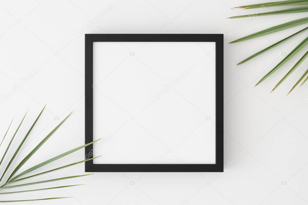 Top view of a black square frame mockup with palm leaf decoration.