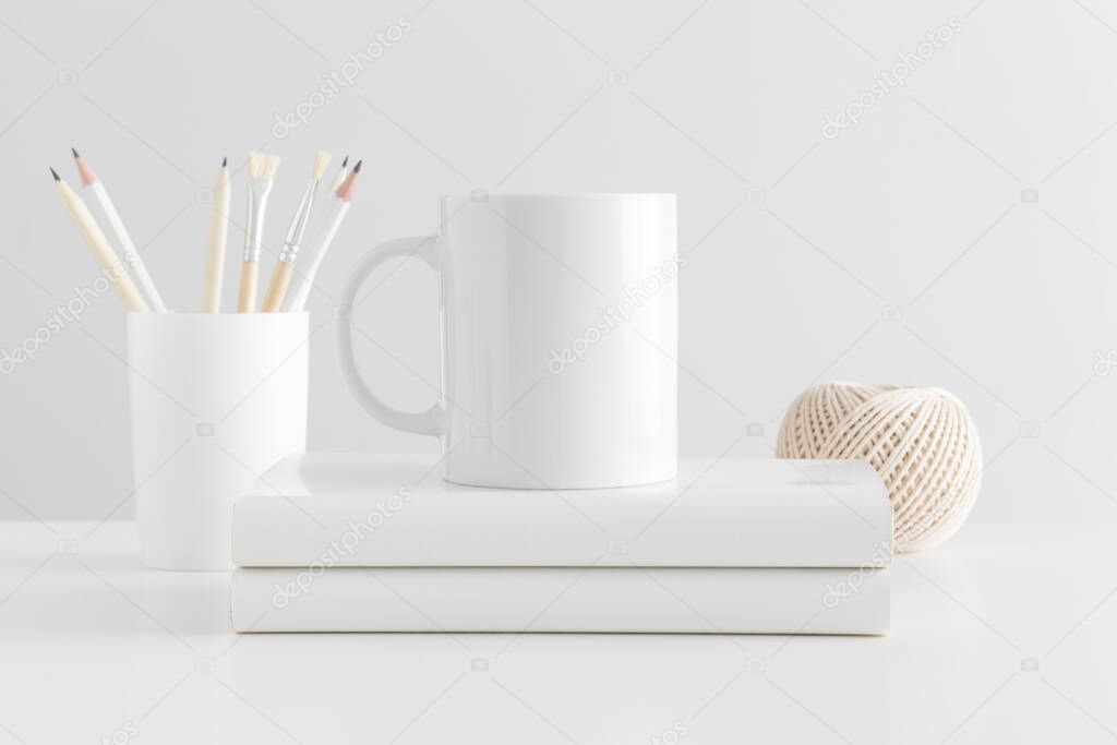 Mug mockup with workspace accessories on a white table.