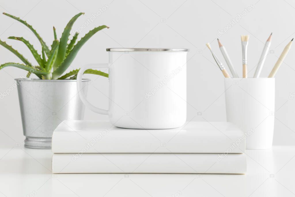 Enamel mug mockup with workspace accessories and a succulent plant on a white table.