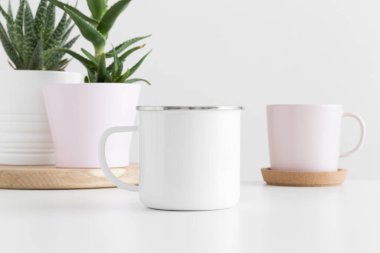 Beyaz bir masa üzerinde çeşitli sulu bitkiler içeren Enamel kupası modeli.