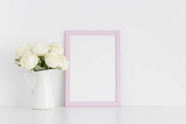 Beyaz bir masadaki vazoda bir buket beyaz gülle pembe çerçeve. Portre oryantasyonu..