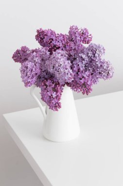 Beyaz bir masadaki vazoda bir demet leylak çiçeği.