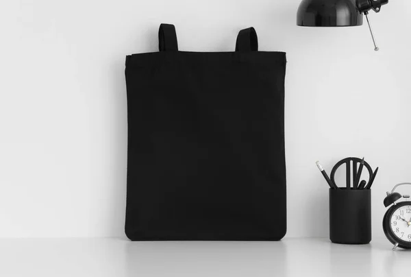 Schwarze Tasche Attrappe Mit Arbeitsplatzzubehör Auf Weißem Tisch — Stockfoto