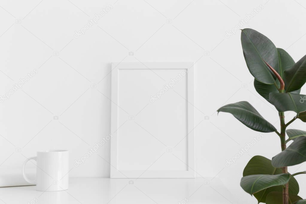 White frame mockup with a mug, book and ficus on a white table. Portrait orientation.