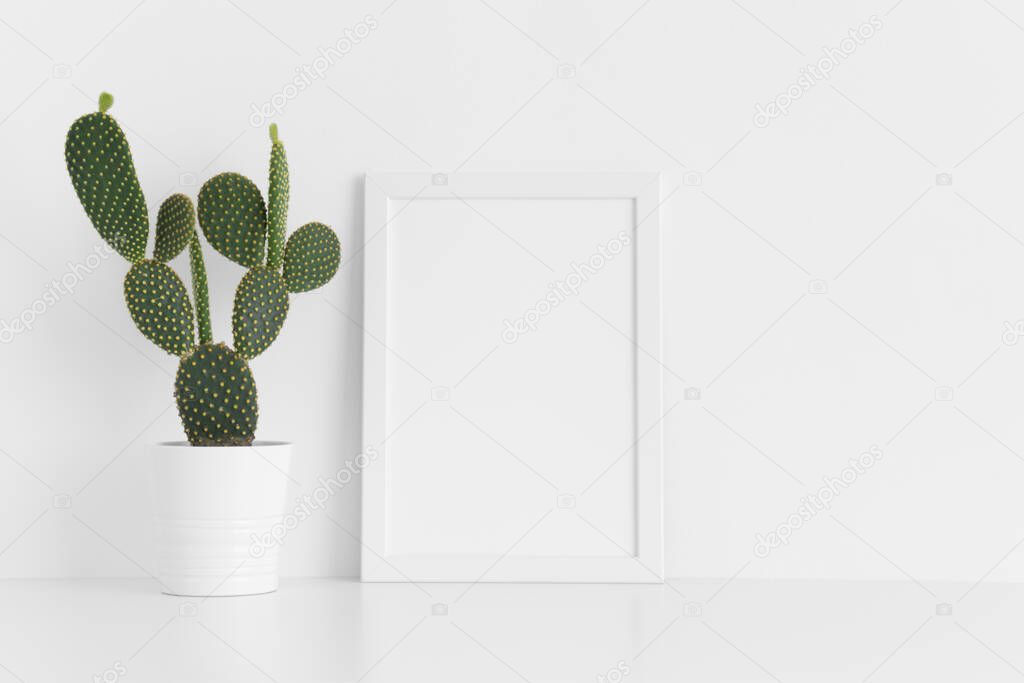 White frame mockup with a opuntia cactus in a pot on a white table. Portrait orientation.