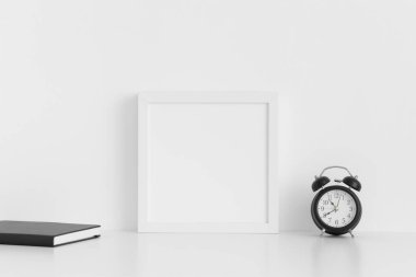 Beyaz masa üzerinde çalışma alanı aksesuarları olan beyaz kare çerçeve modeli.