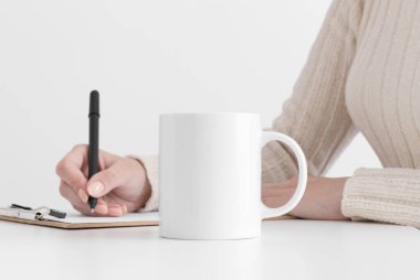 Beyaz kupa, bir panoya not alan bir kadın..