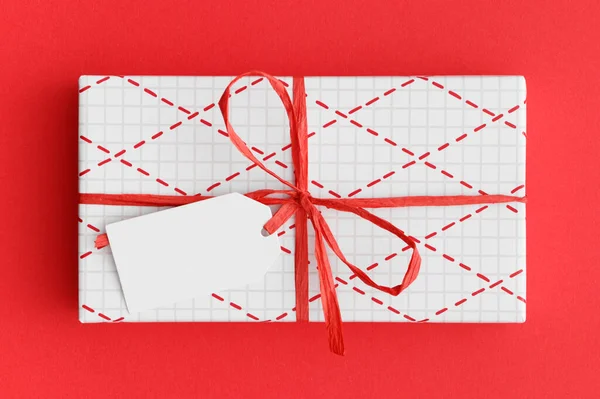 Weiße Weihnachtsgeschenk Mit Einem Leeren Tag Attrappe Auf Rotem Hintergrund — Stockfoto