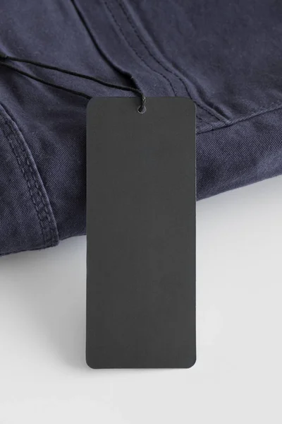 Black clothing tag mockup on a blue pants.