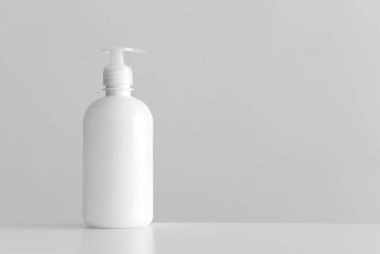 Beyaz kozmetik sıvısı sabunluk şişesi. Beyaz bir masada boş fotokopi alanı var..