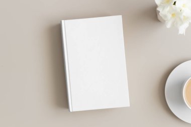 Bir fincan kahve ve bej bir masada zakkum eşliğinde beyaz kitap modeli..