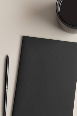 Siyah defter, bej bir masada bir fincan kahve..