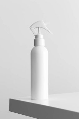 Beyaz kozmetik tetik sprey şişesi beyaz bir masanın üzerinde..