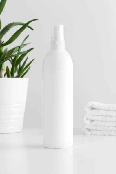 White cosmetic spray bottle mockup with a aloe vera and towels on a white table.