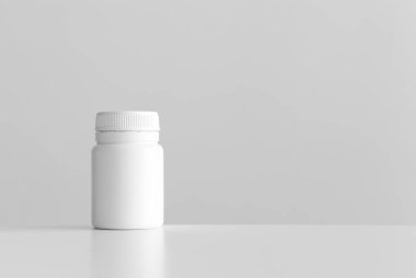 Beyaz bir masanın üzerinde boş fotokopi alanı olan beyaz hap şişesi..