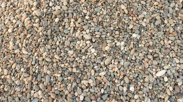 round river gravel of different shades is scattered on a horizontal surface as a textured natural background