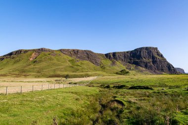 Skye Adası 'ndaki Neist Point' in yanındaki burnun üzerinde mavi bir gökyüzü var.