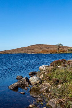 Güney Uist Hebridean adasında mavi gökyüzü ile Druidibeg Gölü 'ne bakıyorum.