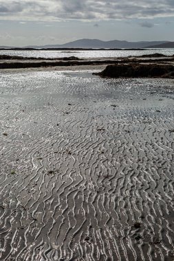 Alçak gelgitte kumsalda dalgalanmalar, Hebridean adası Eriskay 'da bir plajda