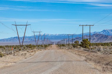 Nevada 'da uzak bir yol. Her iki tarafında elektrik kabloları ve karla kaplı dağlar var.