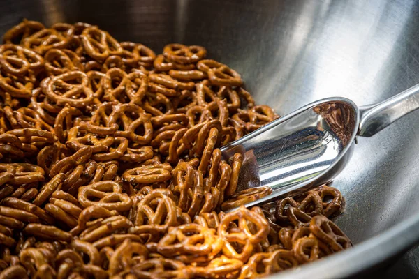 A bowl of pretzels at a bar, with a serving scoop