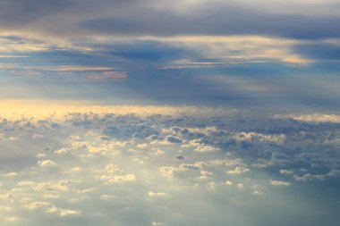 Bulutlar ve akşam ışığı, bir uçağın uçuş güvertesinden görüldüğü gibi.