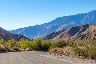 Kaliforniya çölünde virajlı bir yol, etrafını saran engebeli dağlarla