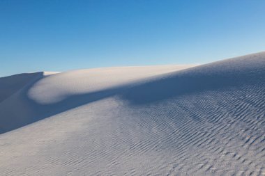 New Mexico 'daki White Sands Ulusal Anıtı' nda mavi gökyüzü ve beyaz alçıtaşı kumları karşı karşıya.