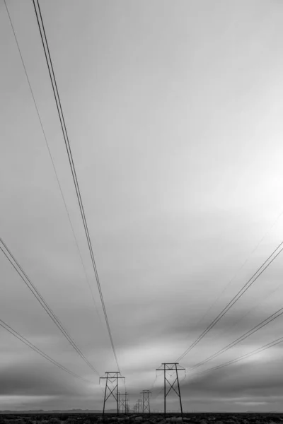 Electricity pylons  in rural New Mexico, against a moody sky