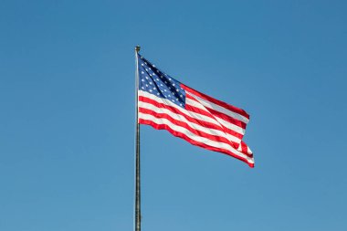 Açık mavi gökyüzünde dalgalanan Amerikan bayrağı