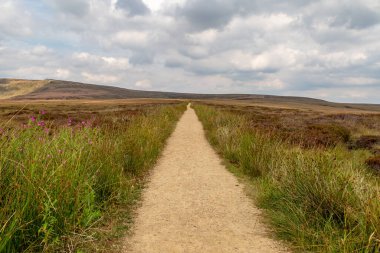 Looking down an empty pathway along the Pennine Way in Derbyshire, with a cloudy sky overhead clipart