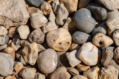 A full frame photograph of pebbles on a beach with one resembling a face clipart