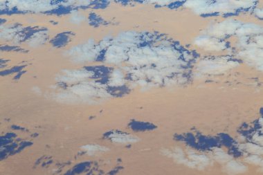 Kumlu bir çöldeki bulutların gölgeleri, bir uçağın uçuş güvertesinden alındı.