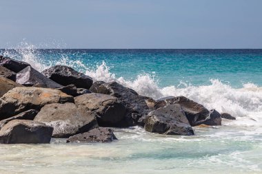 Dalgalar Barbados adasındaki bir sahilde kayaların üzerine düşüyor.