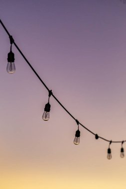 Günbatımı gökyüzüne doğru sarkan bir dizi peri ışığı.