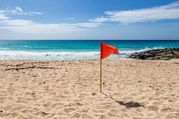 A red warning flag on a caribbean beach