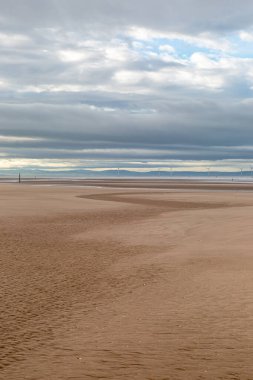 Merseyside 'daki Formby' deki engin boş sahil. Denizde görünen bir rüzgâr çiftliği var.