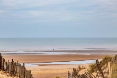 Kum tepelerinin üzerinden kışın kumsal manzarasına bakıyorum.