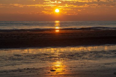Denizin üzerinde dramatik bir gün batımı. Suda bulut gölgeleri var.