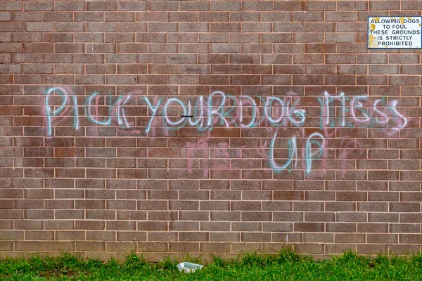 A Pick Up Your Dog Mess sign on an urban brick building