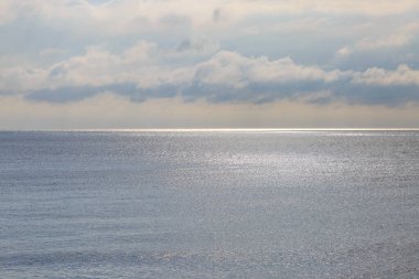 Brighton 'daki sakin deniz, ufukta güneş ışığı parlıyor.