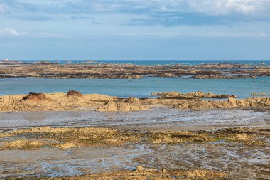 Güneşli bir yaz gününde Jersey adasında kayalık bir kıyı manzarasına bakıyorum.