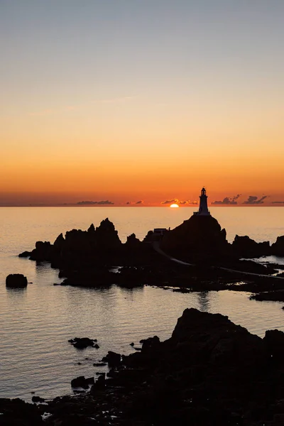 ジャージー島のシルエットのコービー灯台の後ろに沈む太陽 — ストック写真