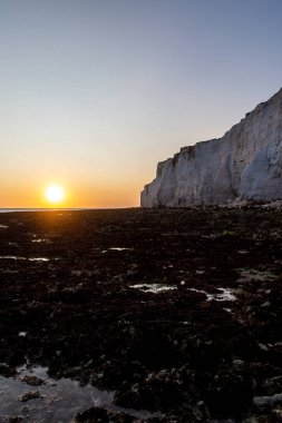 Güneş okyanusun üzerinde batıyor, Sussex kıyısındaki Hope Gap 'tan görülüyor.