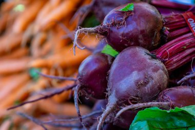 Bir markette satılık pancar pancarı ve arkasında havuç var.