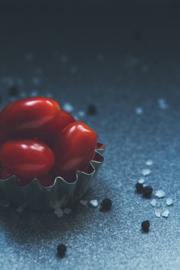 Biraz kırmızı kiraz domatesi. Tuz ve karabiberle tatlandırılmış bir tencere.