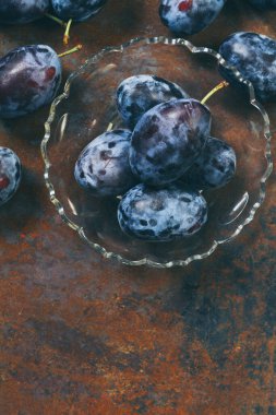 Cam bir tabakta olgun erikler ve gümüş kaşıklar.