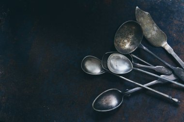 Koyu arkaplanda gümüş renkli çatal bıçak seti, fotokopi alanı olan üst manzara.