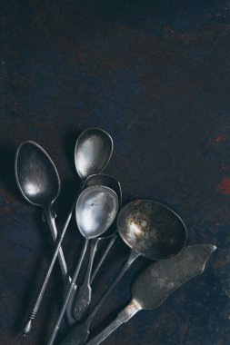 Koyu arkaplanda gümüş renkli çatal bıçak seti, yukarıdan kopyalanmış bir yer.