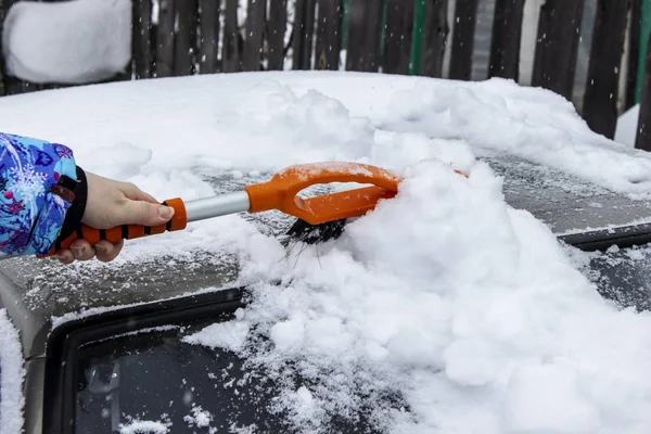 Woman cleans the car from snow brush